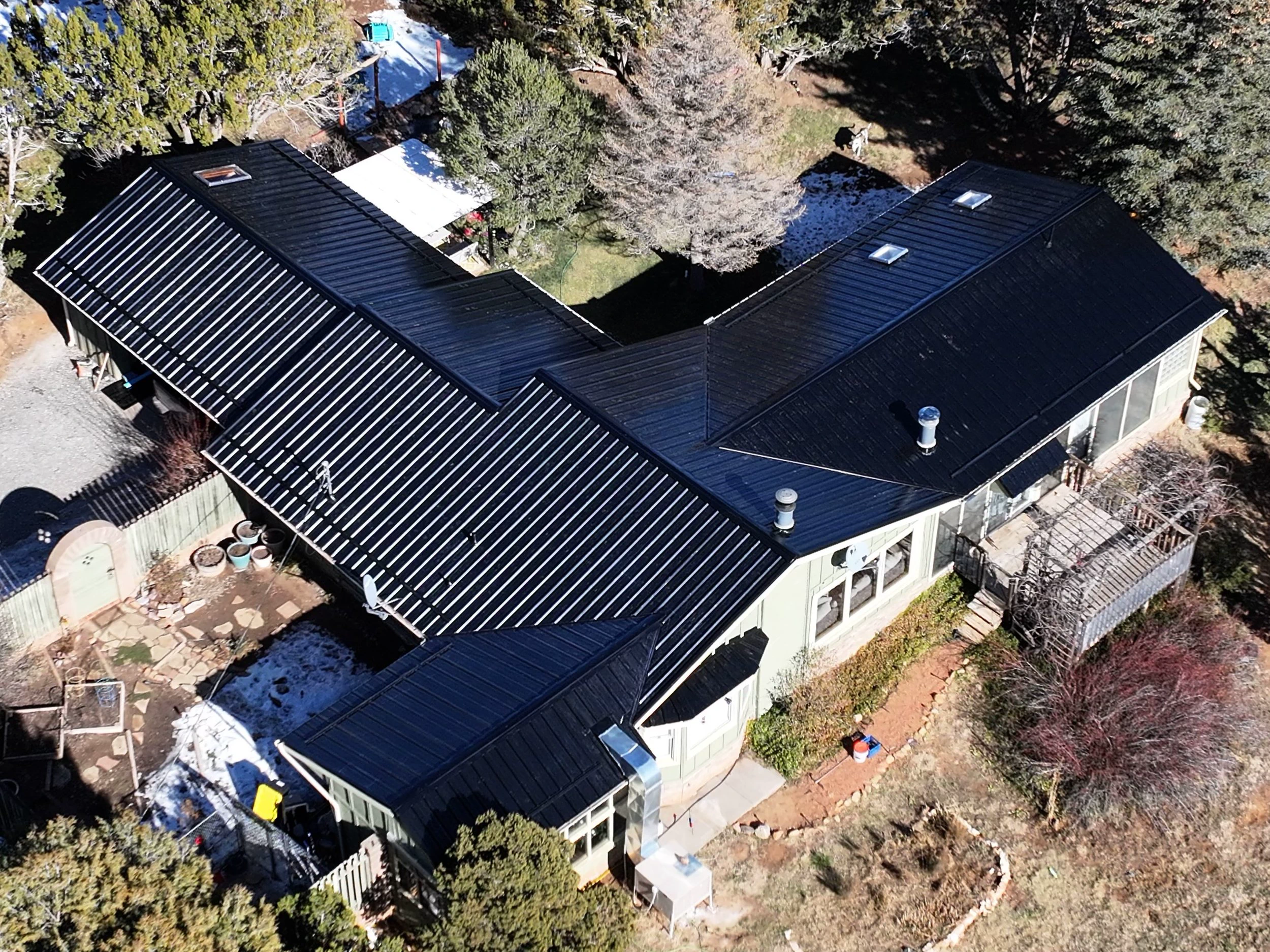 Aerial view of a home with a new black metal roof installed by Desert Storm Roofing