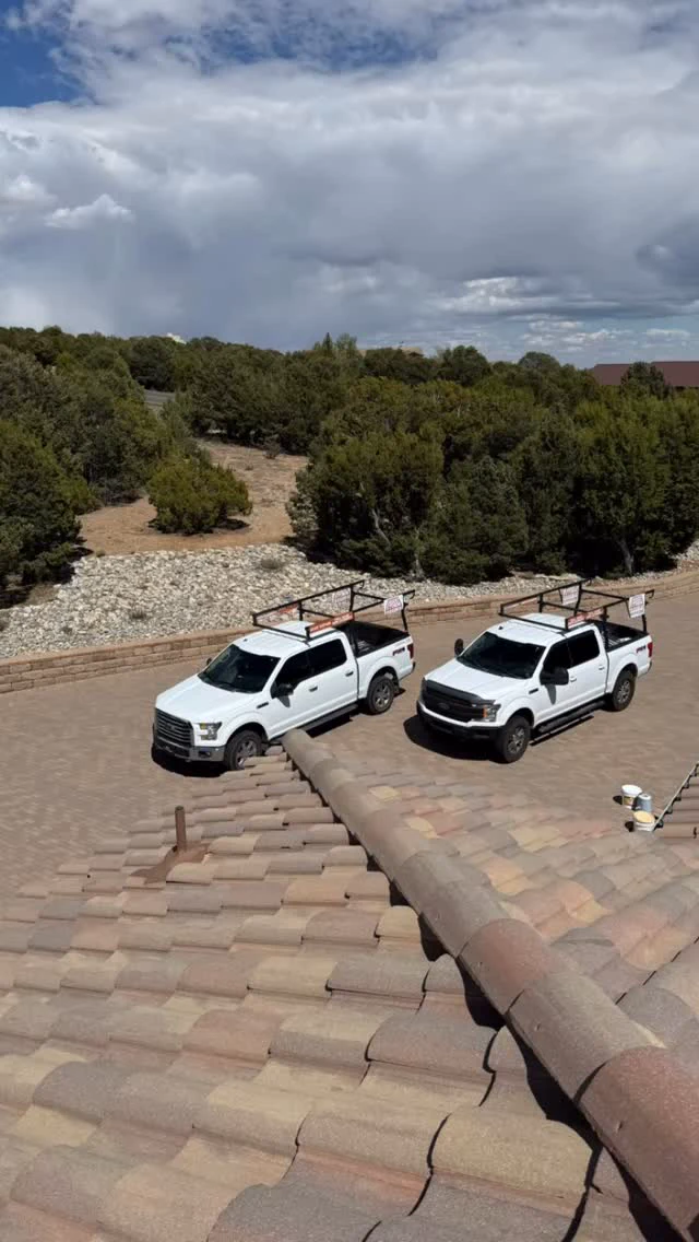 Desert Storm Roofing trucks parked below a roof during changing New Mexico weather